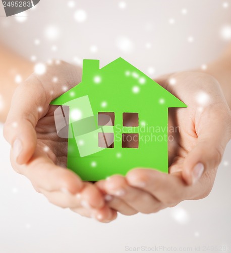 Image of woman hands holding green house