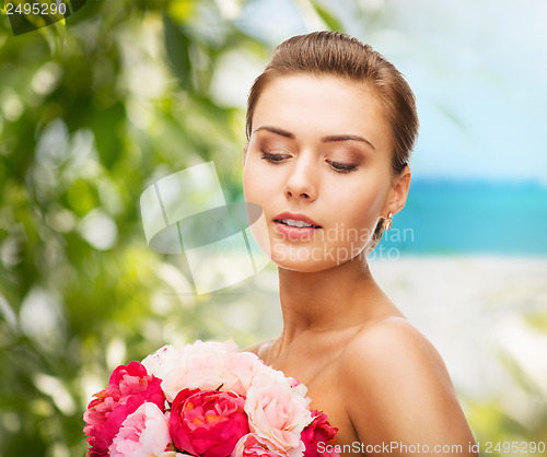 Image of woman wearing earrings and holding flowers