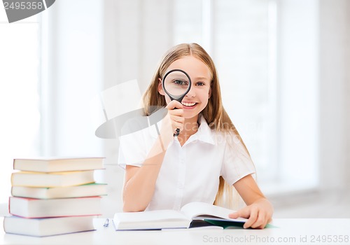 Image of girl reading book with magnifier at school