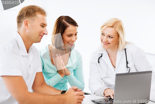 Image of doctor with patients looking at laptop