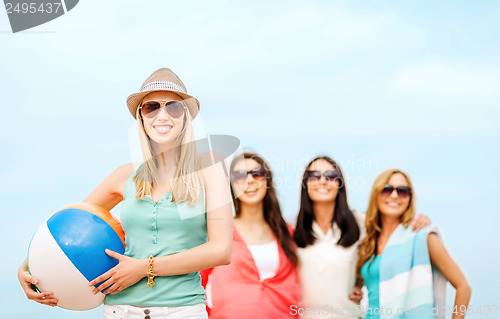 Image of girl with ball and friends on the beach