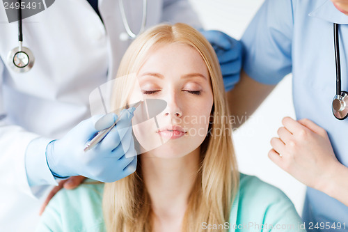 Image of plastic surgeon and nurse with patient