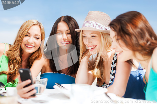 Image of girls looking at smartphone in cafe on the beach