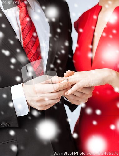 Image of man putting wedding ring on woman hand