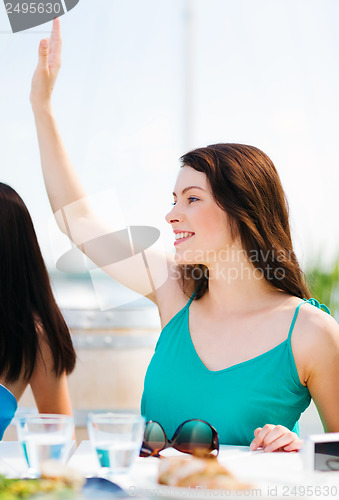 Image of girl waving hand in cafe on the beach