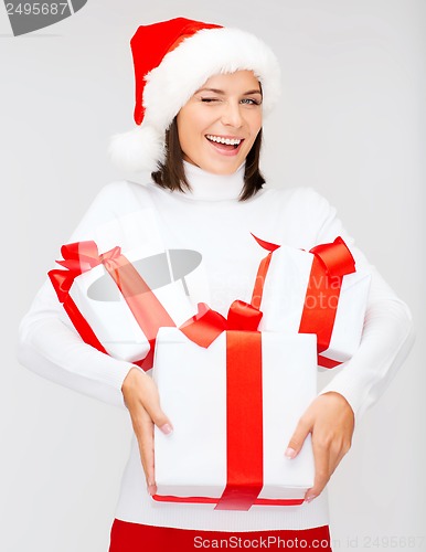 Image of winking woman in santa hat with many gift boxes