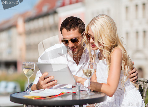 Image of couple looking at tablet pc in cafe