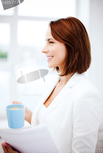 Image of woman with cup of coffee and papers