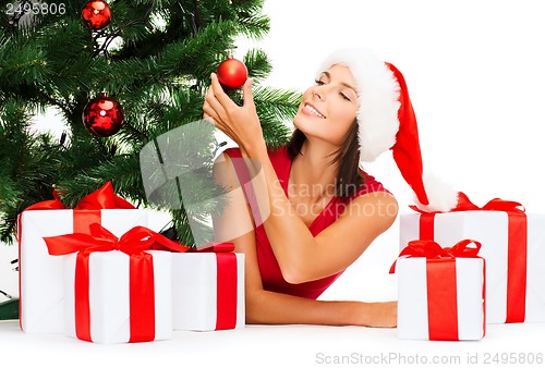 Image of smiling woman in santa helper hat with gift boxes