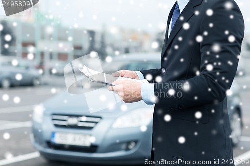 Image of man with car documents outside