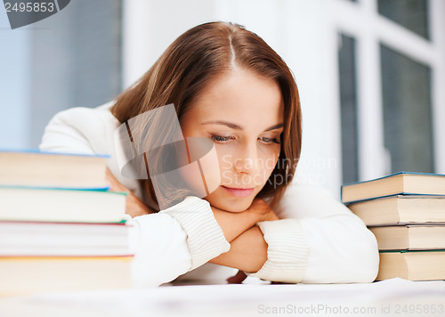 Image of bored young woman with many books indoors