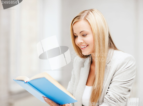 Image of young woman reading book at school