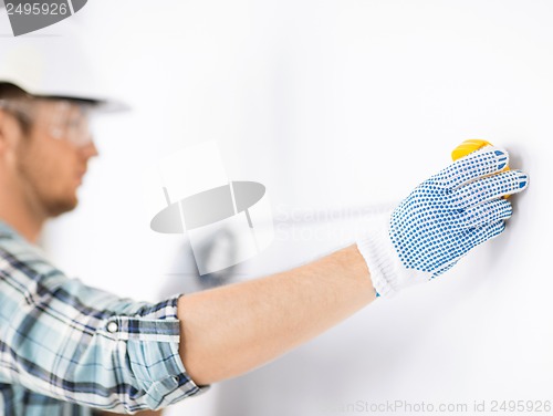 Image of architect measuring wall with flexible ruler