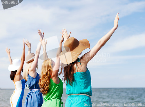 Image of girls looking at the sea with hands up