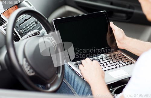 Image of man using laptop computer in car