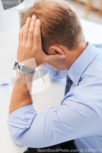 Image of stressed businessman with papers at work