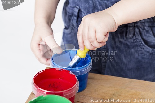 Image of child holding brush in paint tub