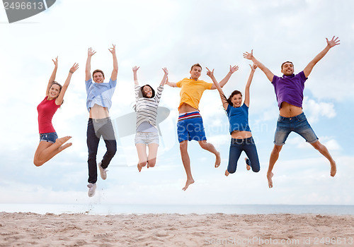 Image of group of friends jumping on the beach