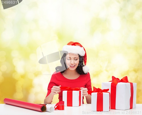 Image of woman in santa helper hat with many gift boxes