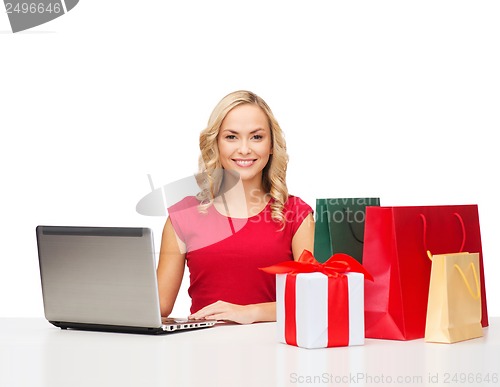Image of woman with gift boxes, bags and laptop computer