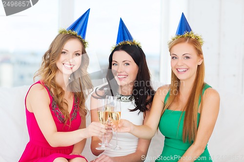 Image of three women wearing hats with champagne glasses