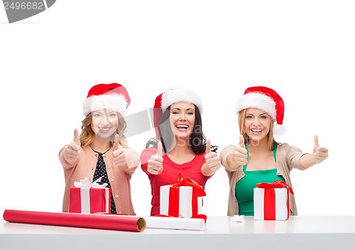 Image of smiling women in santa helper hats with gift boxes