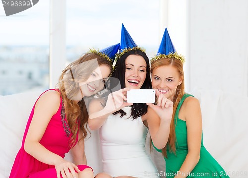 Image of three smiling women in hats having fun with camera