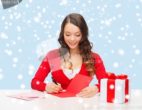 Image of smiling woman in red clothes with postcard