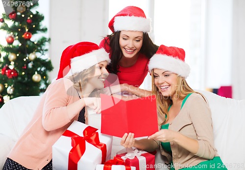 Image of women in santa helper hats with card and gifts