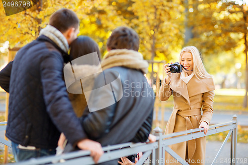 Image of group of friends with photo camera in autumn park