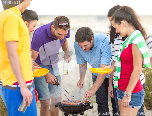 Image of group of friends having picnic on the beach