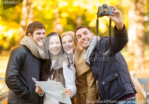 Image of group of friends with photo camera in autumn park