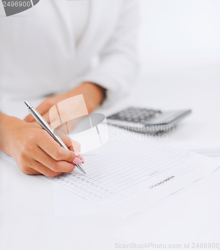 Image of businesswoman working with calculator in office