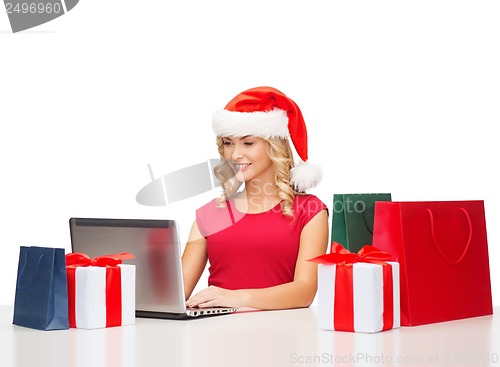 Image of woman with gift boxes, bags and laptop computer