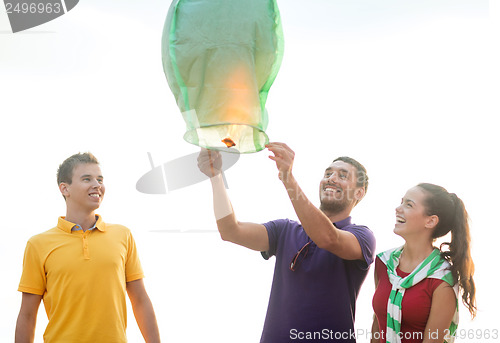 Image of friends with chinese sky lanterns on the beach