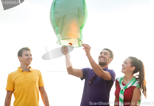 Image of friends with chinese sky lanterns on the beach