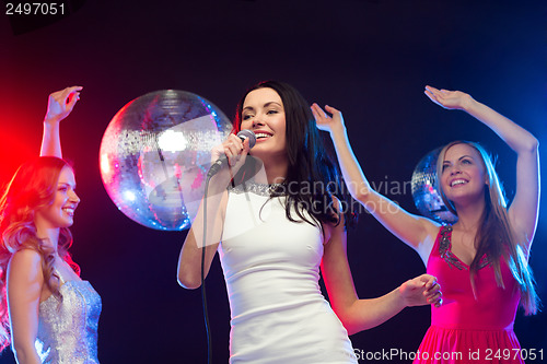 Image of three smiling women dancing and singing karaoke