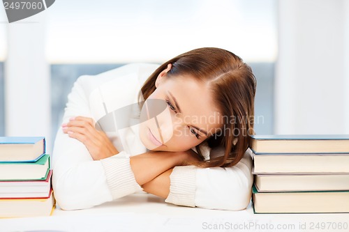 Image of tired student with books and notes