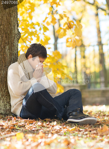 Image of ill man with paper tissue in autumn park