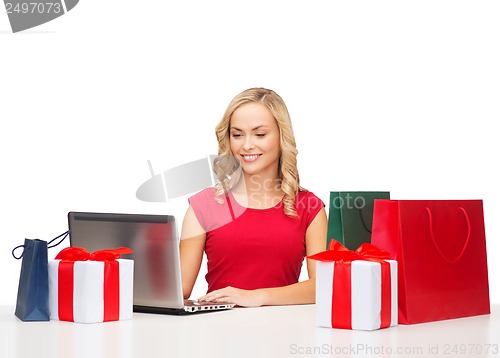Image of woman with gift boxes, bags and laptop computer