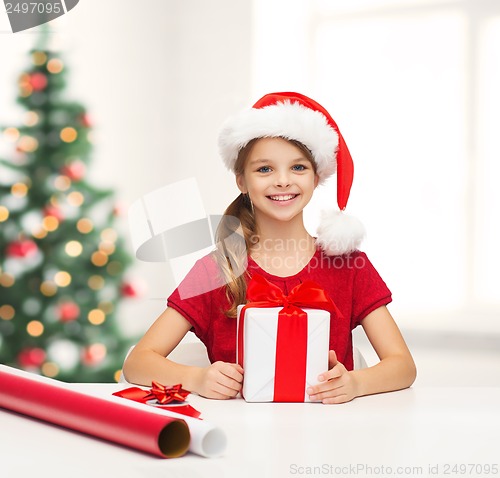 Image of smiling girl in santa helper hat with gift box