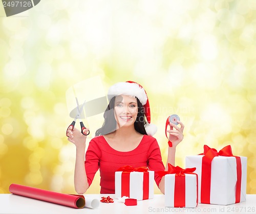 Image of woman in santa helper hat with many gift boxes