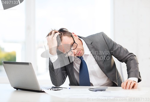 Image of businessman with computer, papers and calculator