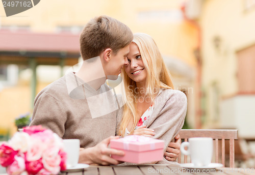 Image of romantic happy couple with gift in the cafe