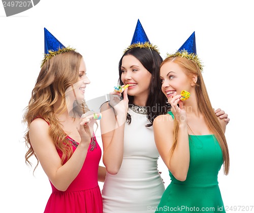 Image of three smiling women in hats blowing favor horns