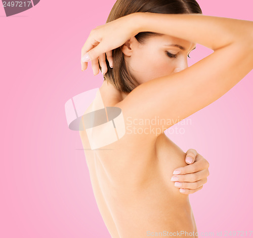 Image of woman checking breast for signs of cancer