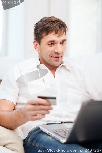 Image of man with laptop and credit card at home