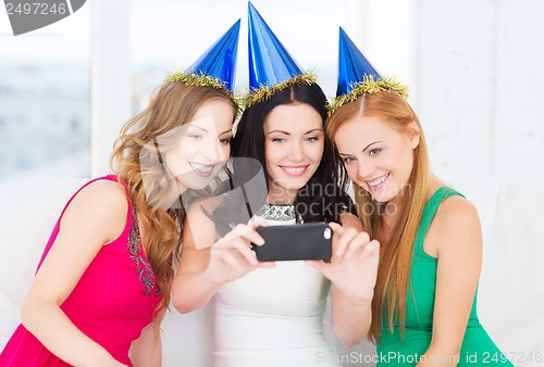 Image of three smiling women in hats having fun with camera