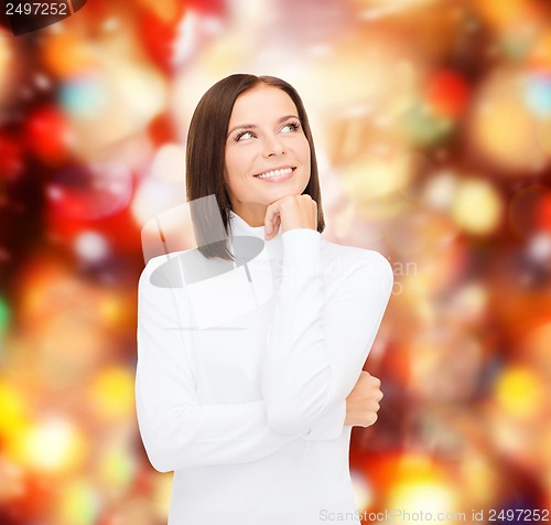 Image of thinking and smiling woman in white sweater