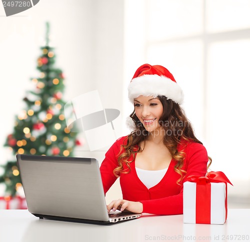 Image of woman with gift box and laptop computer